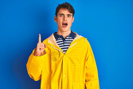 身穿黄色雨衣的青少年渔夫男孩在孤立的背景中与成功的想法指手画脚退出并快乐图片
