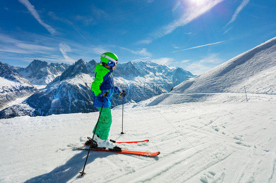 从一个小男孩身后站在高山坡滑雪路上的肖像图片