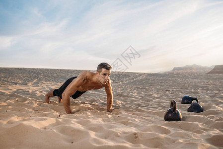 运动员在阳光明媚的日子在沙漠中做俯卧撑练习强烈的运动力图片