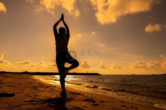 海滩日落时的休眠妇女瑜伽运动和健康的生活方式新的白图片