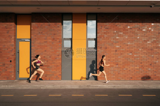 年轻女子早上在人行道上奔跑健康意识的概念健康积极的生活方式活跃的女孩们在城市的道图片