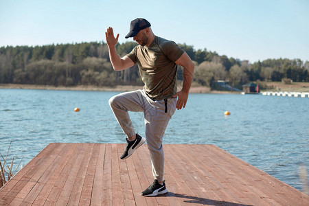 一个穿着运动服的健壮的男人在湖边的码头上做运动一个男人做运动运动健图片