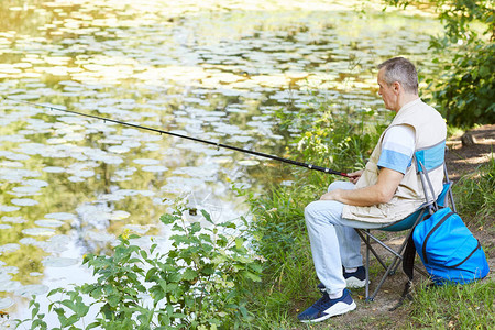 在湖边自然地与渔棍一起在湖边捕鱼的坐在椅子图片
