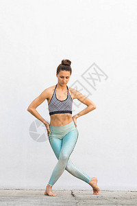 穿着时装运动服在灰墙前做瑜伽健身锻炼户外运动和城市风格的图片