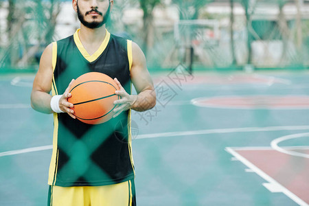 年轻篮球运动员拿着球在户外法庭周围透过图片