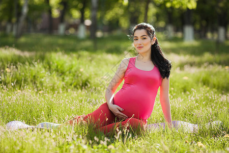 有吸引力的年轻孕妇在公园户外做瑜伽练习期待女拥有健康和积图片