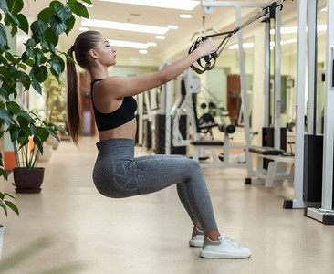 身材苗条的女人正在健身房里用健身带训练健康的生活方式概图片
