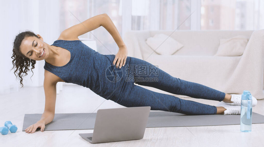 快乐的拉丁女在家看笔记本电脑运动视频的同时图片
