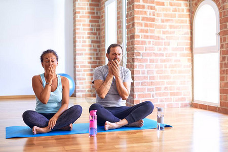 坐在床上的中年运动夫妇在健身房里做伸展瑜伽锻炼图片