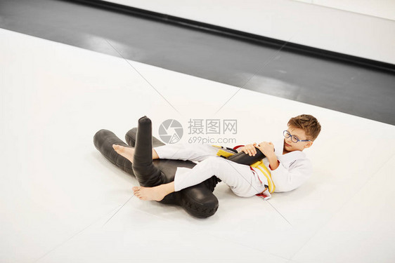 和服中小男孩躺在地板上在柔道训练期间图片