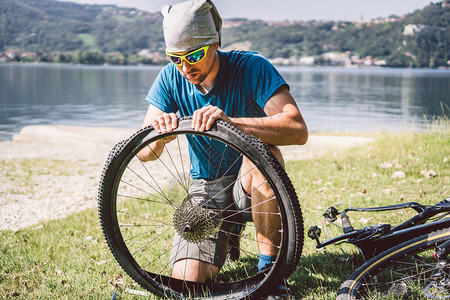 自行车修理修理山地自行车的人骑自行车的人在事故后轮案例中遇到麻烦人在意大利背景山湖附近修理自行车骑自行车的人在户外修图片
