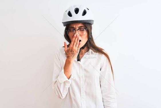 身戴眼镜和自行车头盔的漂亮女商人在孤立的白色背景上无聊地打哈欠图片