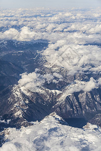 云中阿尔卑斯山脉白雪皑的山顶鸟瞰图图片