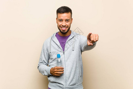 年轻混血的亚裔男子拿着水瓶欢笑的图片