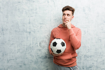 年轻体育运动员拿着足球放松思考一些东西看一个复制空间笑声图片
