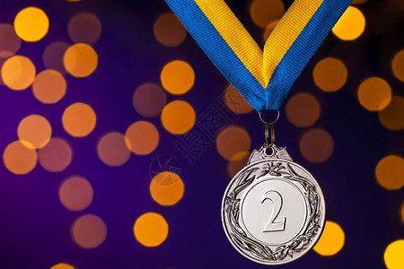银第二名赛跑冠军奖章悬在蓝色背景的丝带上彩色橙斑点和派对灯图片