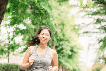 快乐的年轻健康亚裔女在公园户外跑步慢跑训图片