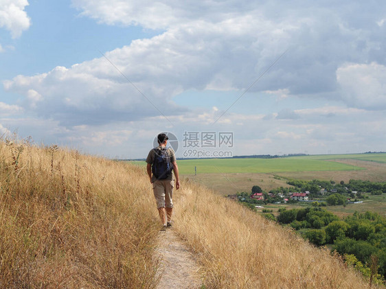 一名年轻男旅游者带着背包在公园中行走图片