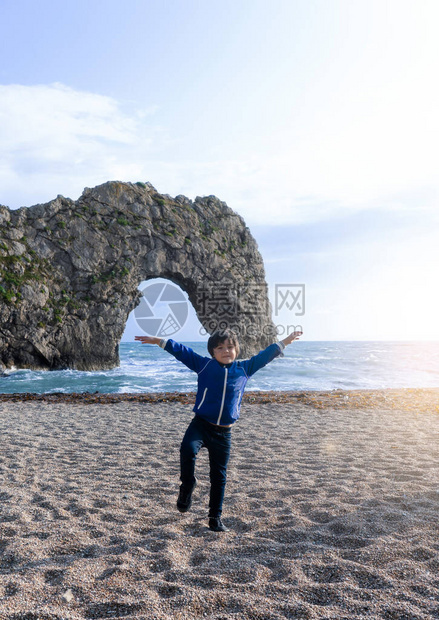 肖像可爱的孩子男孩做瑜伽站在海边模糊的杜德尔门背景图片