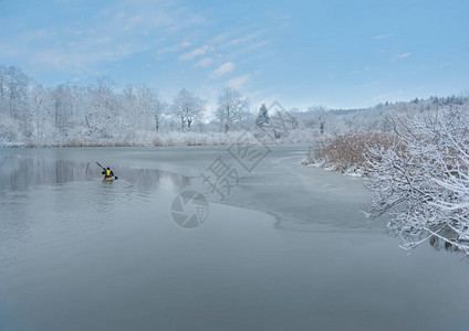 男人在黄色的皮艇上在部分冷冻的河流里图片