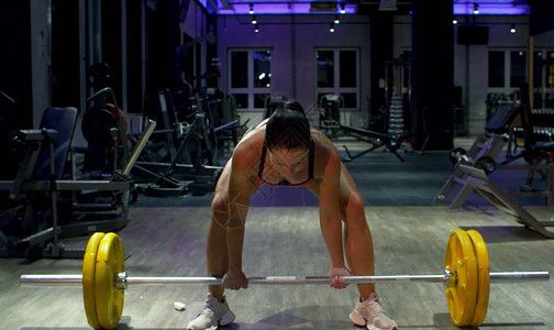 女子健美运动员举杠铃健身房里的运动员健身运图片