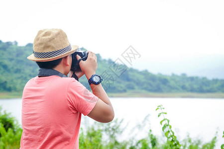 一个戴着帽子的小亚裔男孩喜欢去自然世界旅行拿着相机拍图片