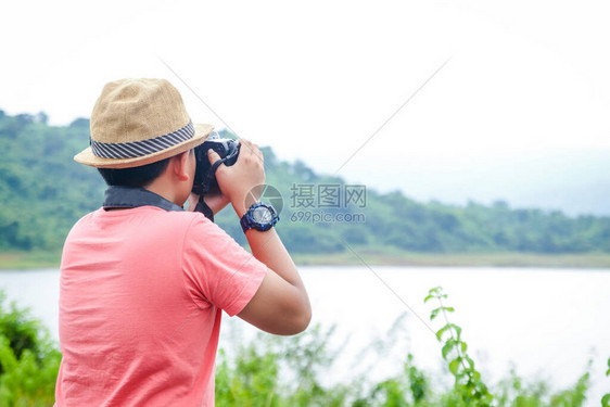 一个戴着帽子的小亚裔男孩喜欢去自然世界旅行拿着相机拍图片