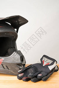 摩托车防护装备木制背景上的越野摩托车头盔和手套垂直方向复图片