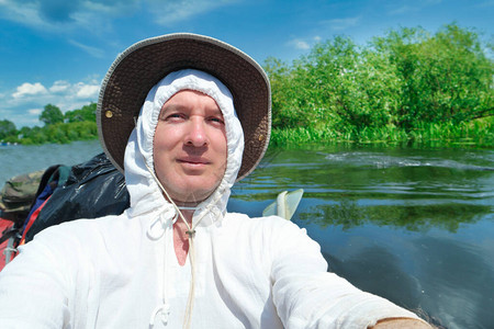 穿着白帽和子的笑脸男子在夏河探险之旅期间在皮艇上图片