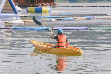 穿着橙色救生衣的年轻女子在湖上划皮艇快乐的年轻女子在水上背景图片
