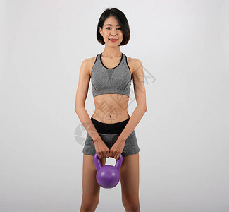 运动服与壶铃做健身锻炼在白色背景上的亚洲运动型女人健康的图片