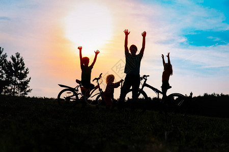 在日落时骑自行车和摩托车的快乐家庭图片