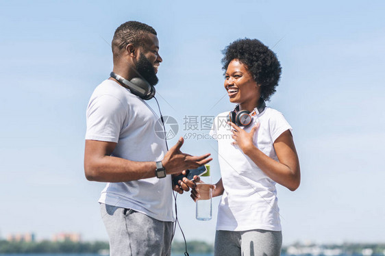 非裔妇女与近河外的个人教练讨论慢跑方案图片