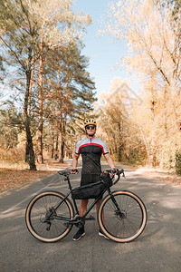 骑自行车的年轻人站在秋天森林的路上图片