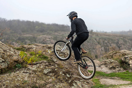 山地自行车上的赛车员正在攀登岩石地形图片