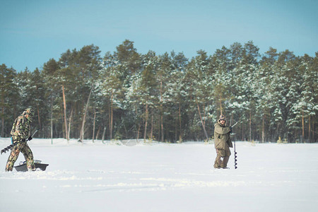 冬天季捕冬钓鱼两个渔民在森林背景下图片