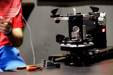 调节羽毛球拍线张力的专用设备一个年轻人正在修理羽毛图片