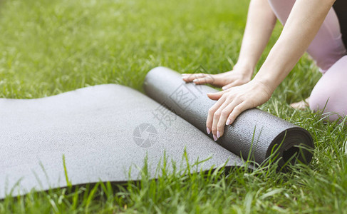 体育女青年在公园工作后折灰瑜伽或健身席图片