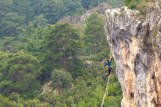 一个女人正沿着一条拉长的吊索行走山中的高线女人抓住了平衡走钢丝者在大图片