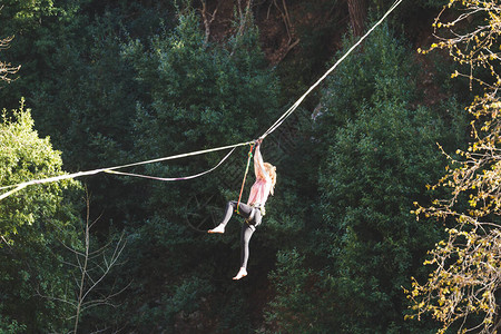 女孩跌倒在拉伸的吊索上山中的高线女人失去了平衡自然界中的演讲走钢丝者Highliner挂在绳子上图片