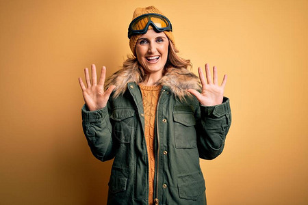 身穿雪运动服和滑雪护目镜的中年金发美女滑雪女郎展示并用手指着十指图片