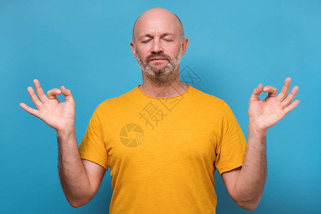 集中精力的大胡子男人在蓝色背景下冥想图片