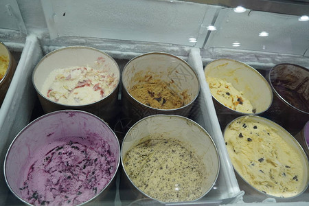 散装冰淇淋放在冰淇淋店玻璃后面的大圆形容器中冰淇淋在糖果店开心果