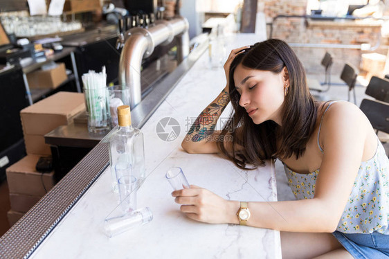 酒醉女顾客在酒吧用空杯子图片