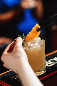 酒保用橙片装饰清爽的冷鸡尾酒特写图片