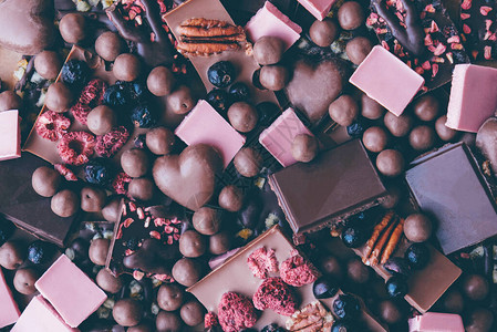 各种巧克力棒一堆深色牛奶粉红色的巧克力和巧克力与水果和坚图片