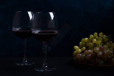 两杯红酒和两杯葡萄在黑色图片