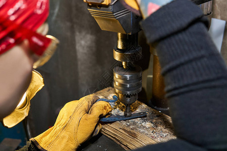 手工艺女工匠在装配反辛克切割机的钻井机上操控金属艺术品图片