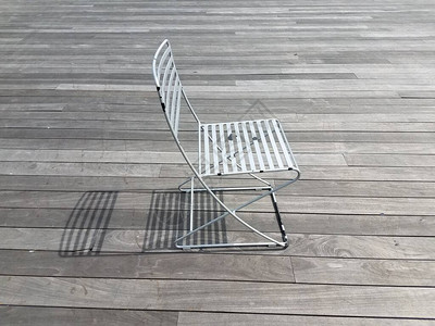 金属椅子在木板路上投下阴影背景图片