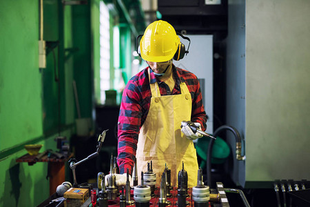 带安全帽和眼镜的工厂人挑选设备或工具在钢铁制造厂的车床上工作五金及零图片